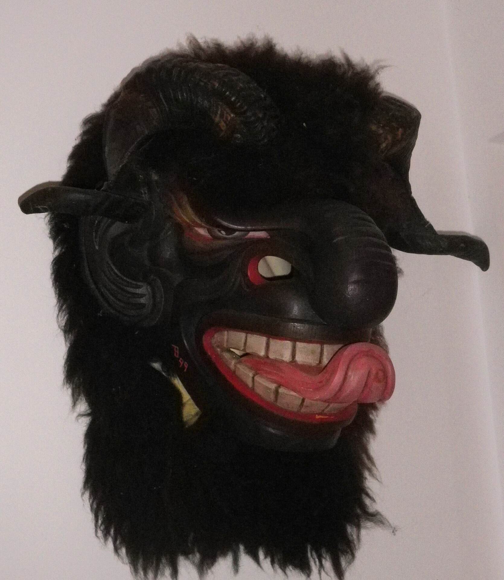 Handgeschnitzte Krampusmaske aus Holz mit Hörnern, Fell und herausgestreckter Zunge